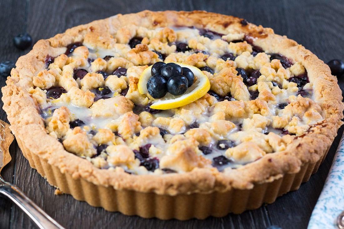 Blueberry Pie just got a sweet and lemony makeover with this recipe for Blueberry Lemon Shortbread Tart. This tart has a buttery, lemon infused, melt in your mouth shortbread base with a luscious, sweet blueberry filling. To top it off, a crumble of the lemon shortbread. It's a summer dessert you won't soon forget.