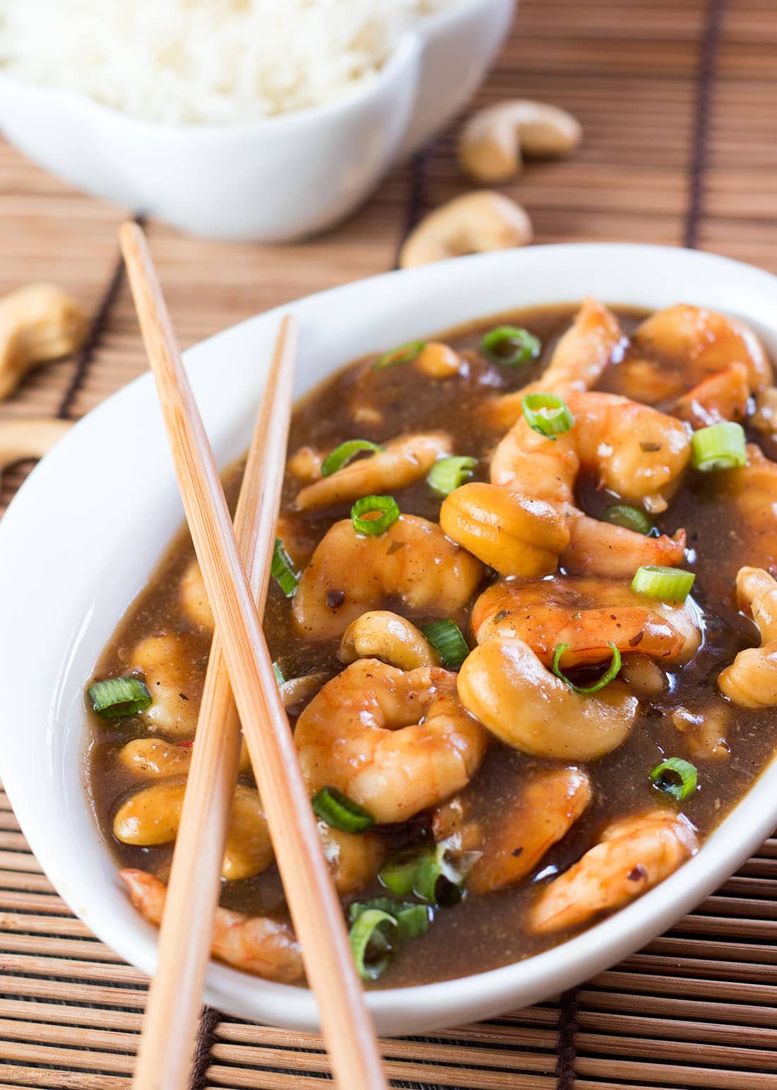 Cashew shrimp in a bowl with a bowl of fluffy rice in the background