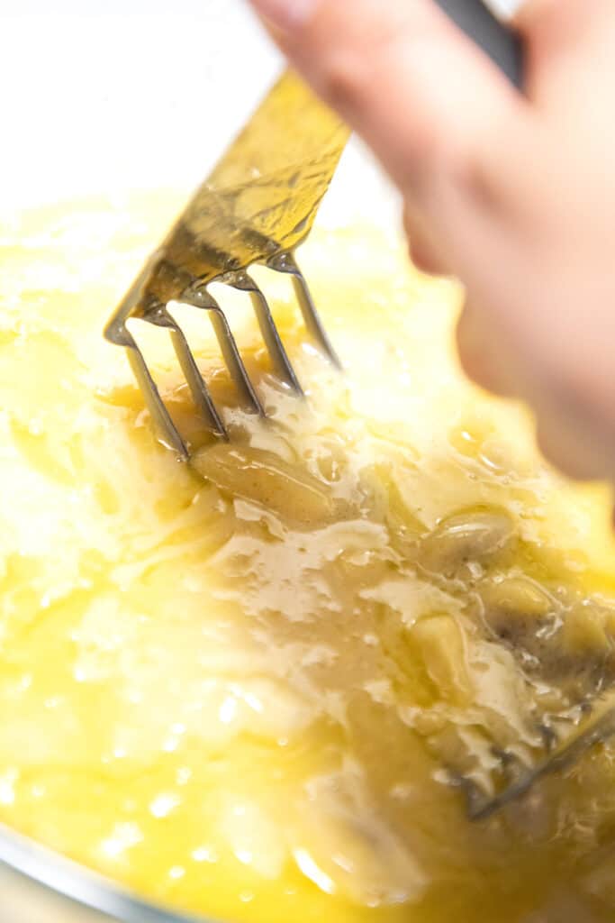 banana being mashed into melted butter