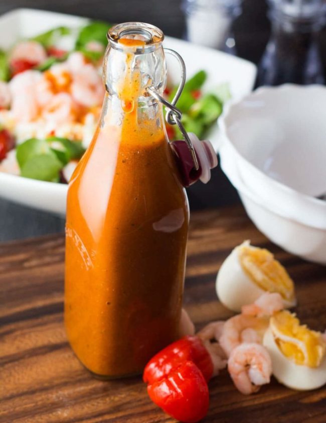 the salad dressing in a bottle with salad fixings all around it