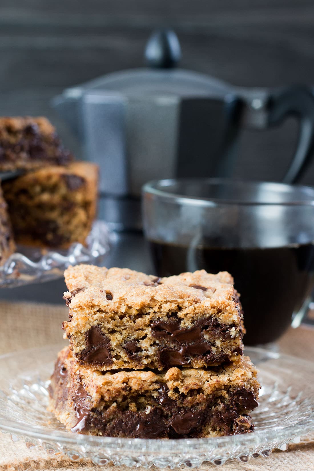 fresh out of the oven Chocolate Chip Spiced Oat Bars showing melted chocolate chips with a pot of coffee in the background 