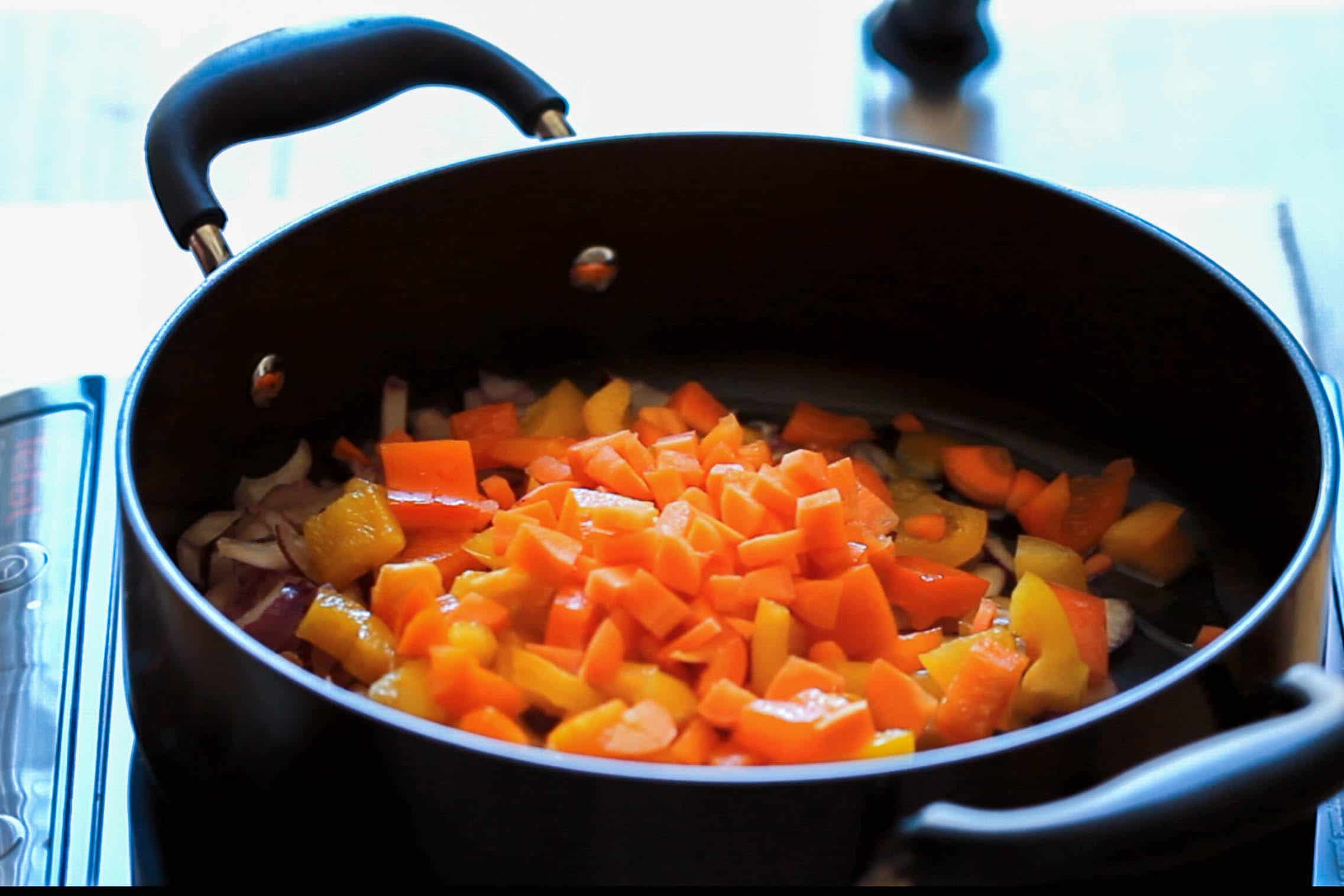 Diced carrot added to the pan with the peppers and onions