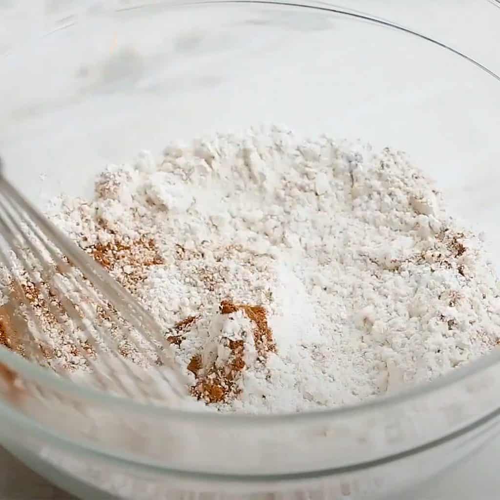 the dry ingredients in a bowl being mixed with a whisk