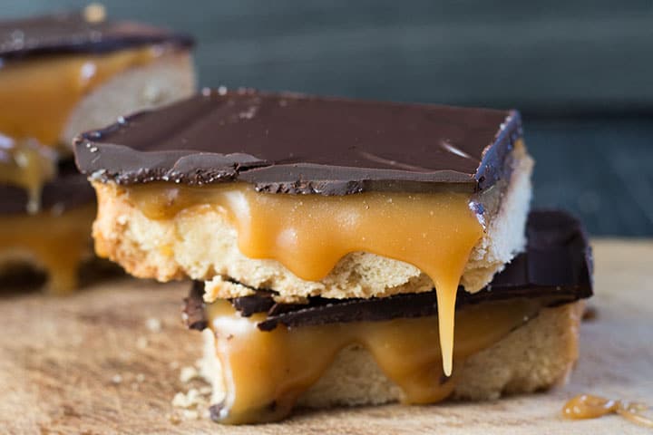 two pieces of billionaires shortbread on top of each other with caramel dripping down