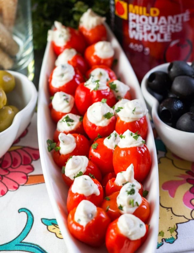 A plate of the stuffed peppers with bowls of olives on either side.