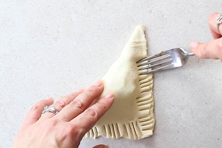 The dough being sealed around the turnover with a fork