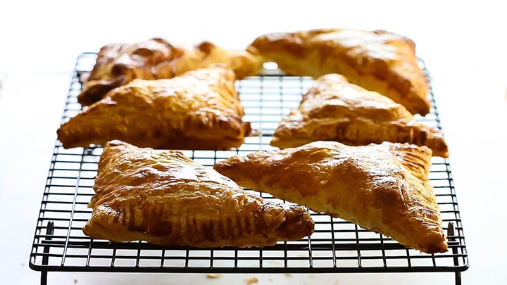 Apple Turnovers that are crisp and golden brown cooling on a wire rack.