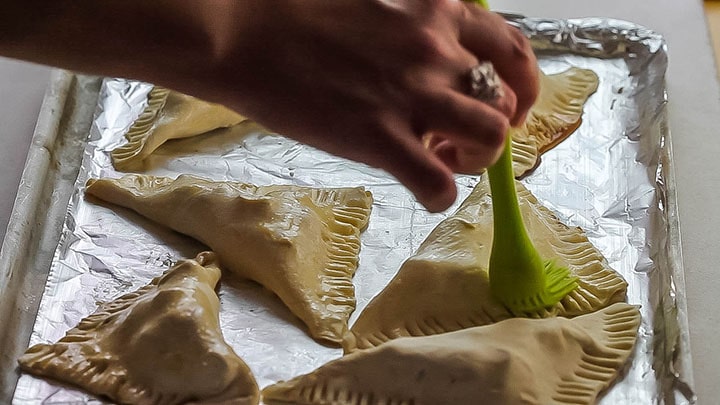 Apple Turnovers being brushed with the egg wash.