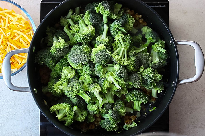 The broccoli added to the pan with the spices, onion, and garlic