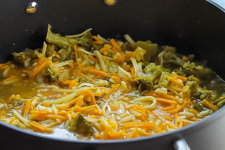 The cheese melting into the soup in the pan