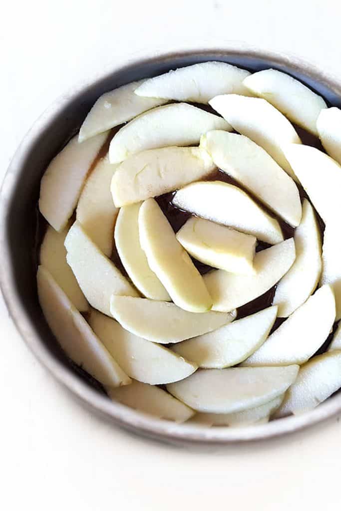 the apples arranged in the sauce in the pan