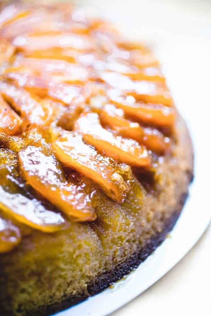 a close up shot of a cake topped with golden baked apple slices