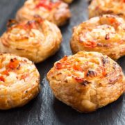 A close up of two rows of feta and sweet pepper pastry swirls