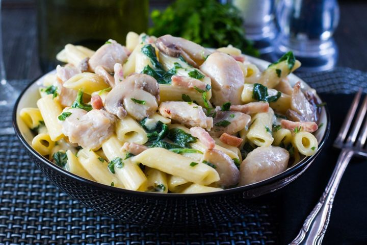 Creamy Chicken and Bacon Pasta piled high in a pasta bowl with a fork next to it.