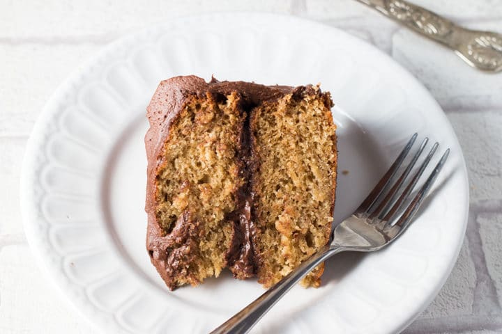 Banana Spice Cake with Chocolate Fudge Frosting on a plate with a fork beside