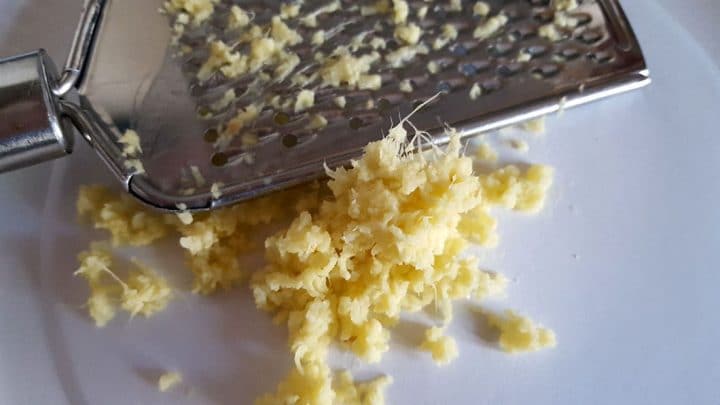 Fresh grated ginger on a plate with the grater,