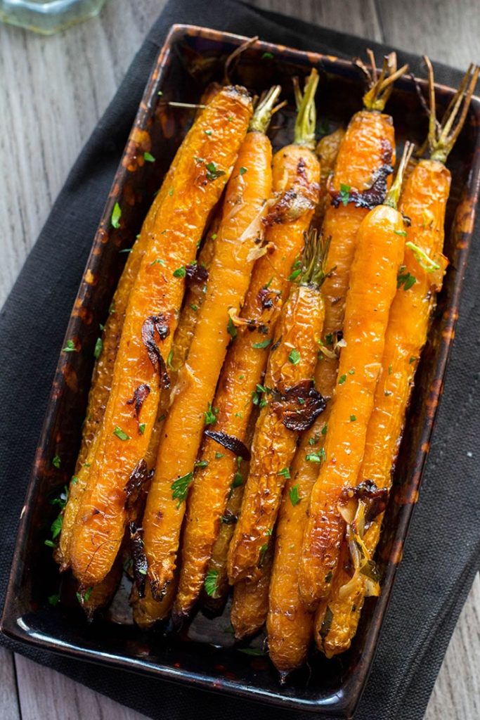 Buttery Balsamic Garlic Roasted Carrots on a serving dish sprinkled with parsley