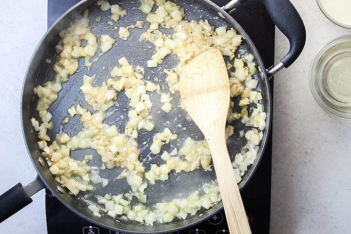 A pan with onions and garlic cooking in olive oil. and butter