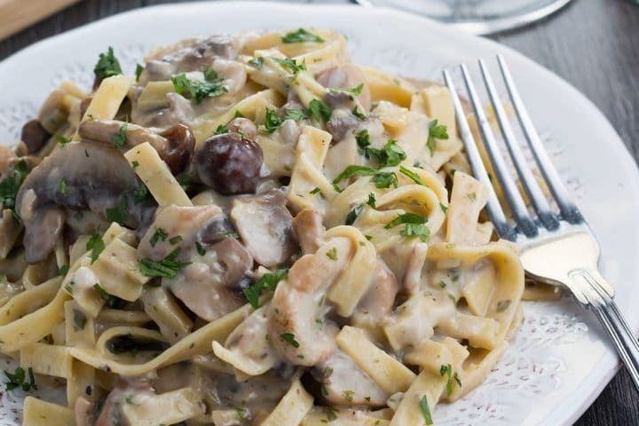 A plate of Creamy Tagliatelle and Mushrooms on a plate with a fork next to it.