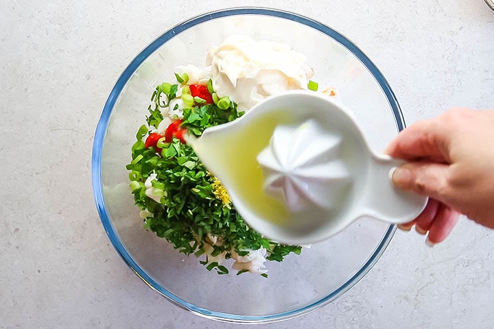 The lemon juice being added to the crab mixture in the bowl