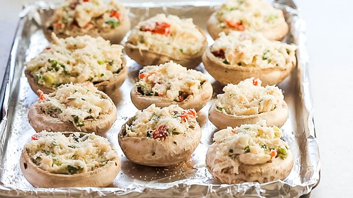 Easy Crab Stuffed Mushrooms sprinkled with Parmesan cheese and ready to bake 
