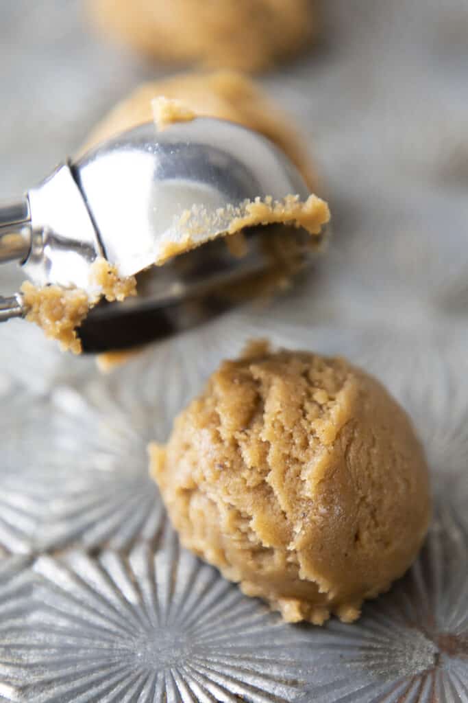 a cookie scoop placing Ginger Crinkle Cookie dough onto a cookie sheet