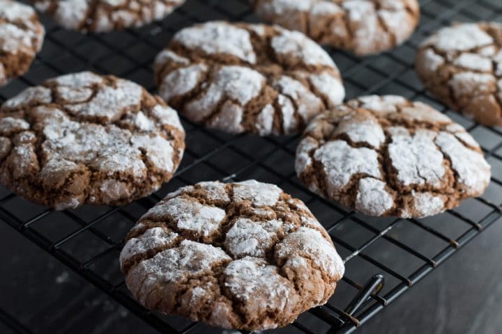 Spiced Ginger Crinkle Cookies fresh out of the oven cooling on a cooling rack.