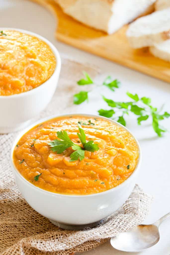 carrot soup in a bowl with a second bowl in the background