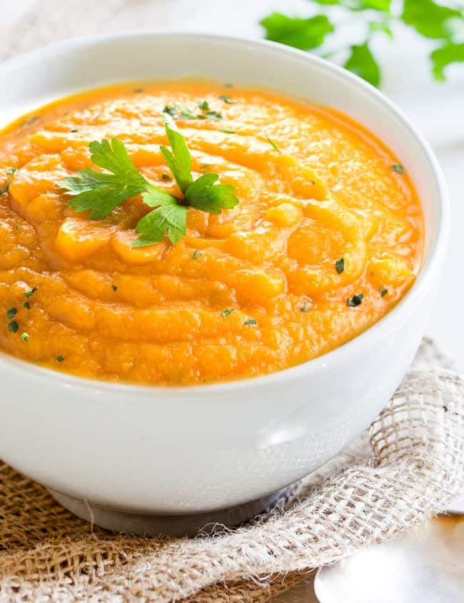 carrot soup in a bowl topped with fresh herbs