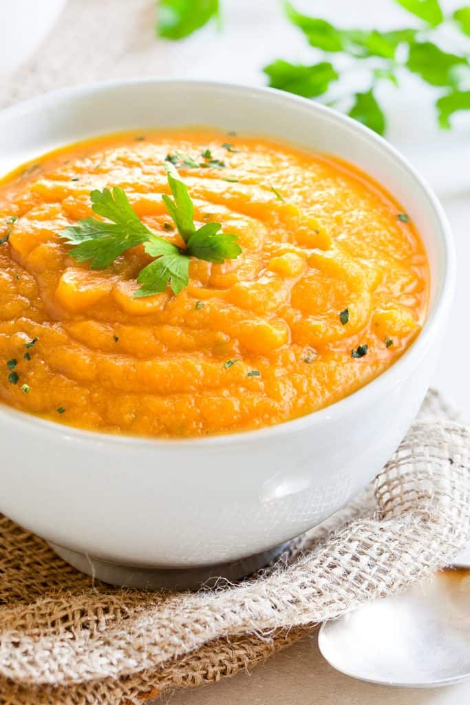 carrot soup in a bowl topped with fresh herbs