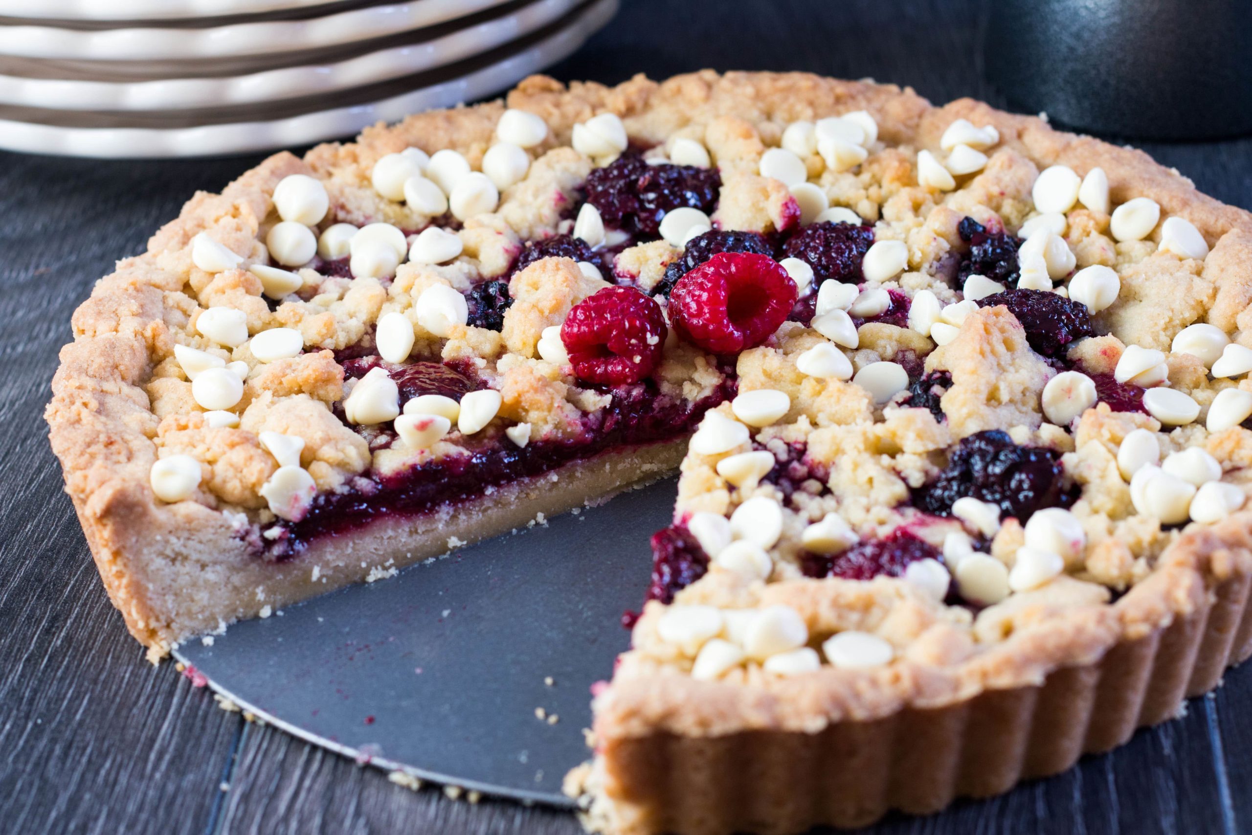 Raspberry and White Chocolate Shortbread Tart with a slice cut out of
