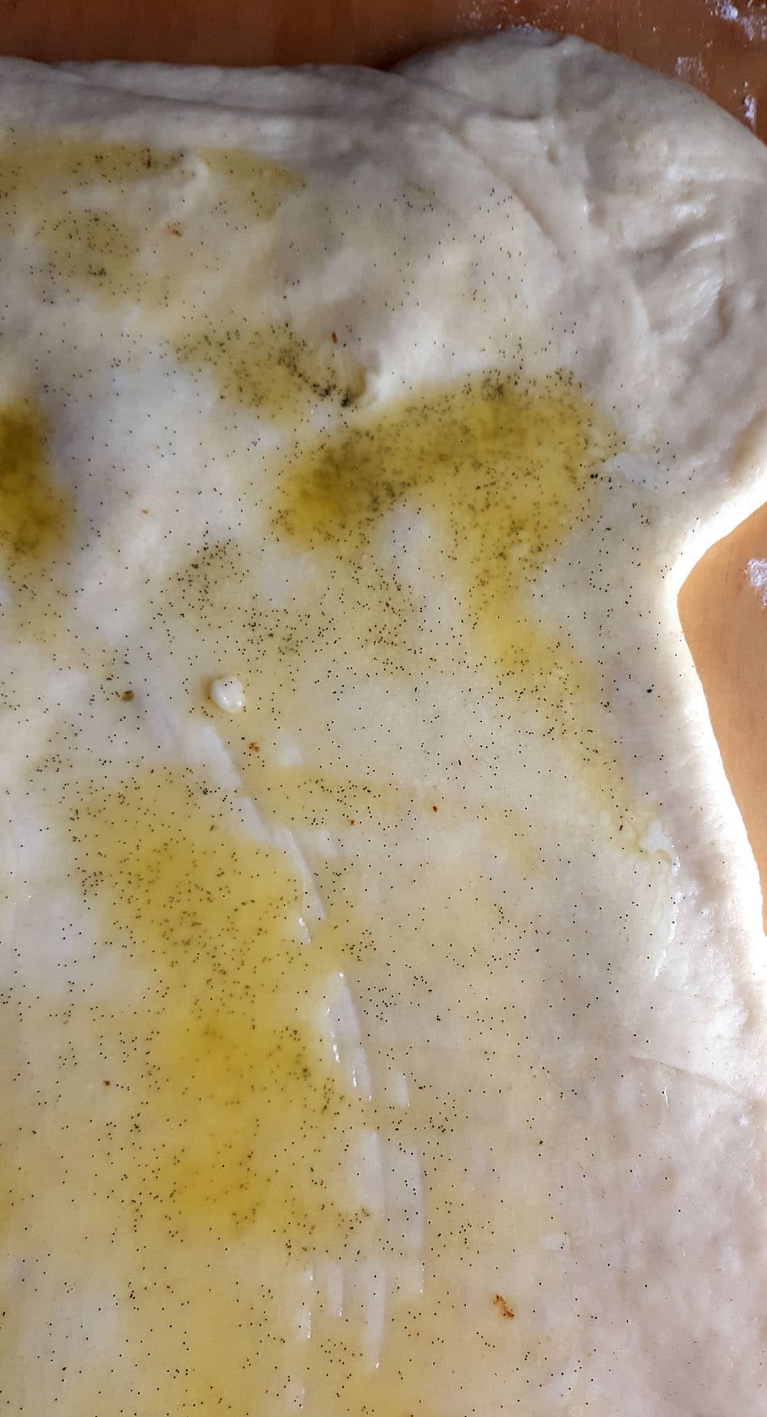 Rolled out dough covered in melted butter and speckled with vanilla beans