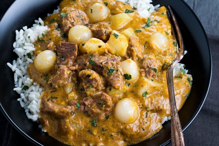 Beef Massaman Thai Curry with rice in a black bowl with a fork