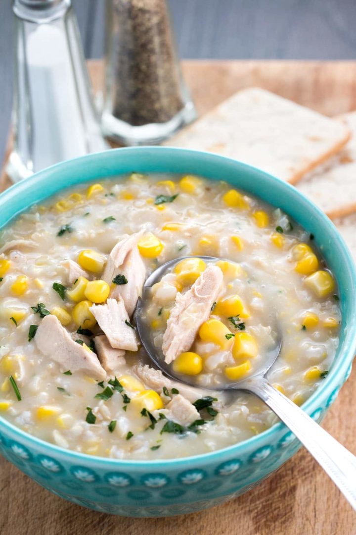 a close up of chicken and rice corn chowder with a spoonful being taken out of it
