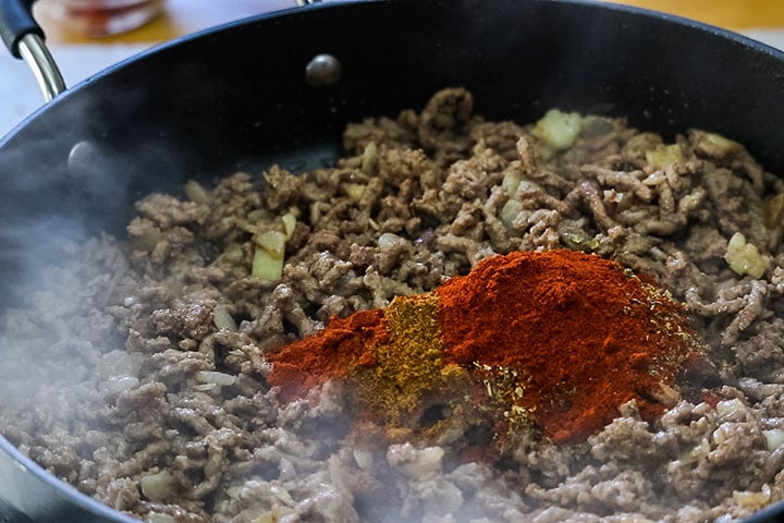 The spices added to the ground beef in the pan