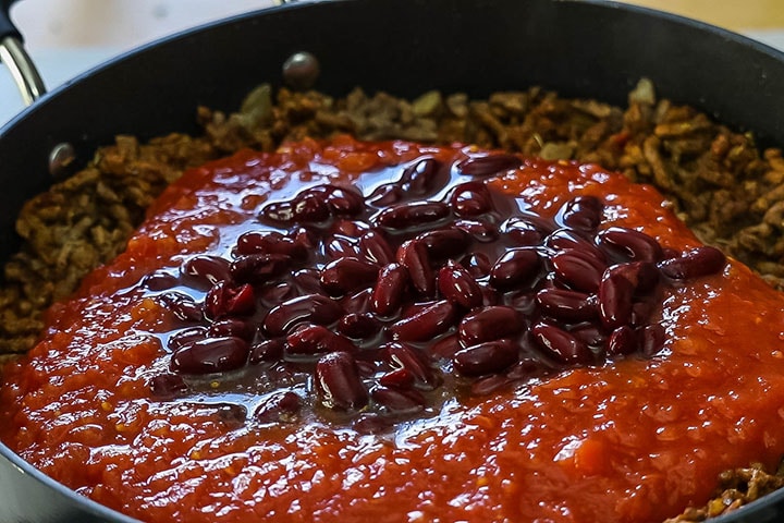 The tomatoes and beans added to the meat in the pan