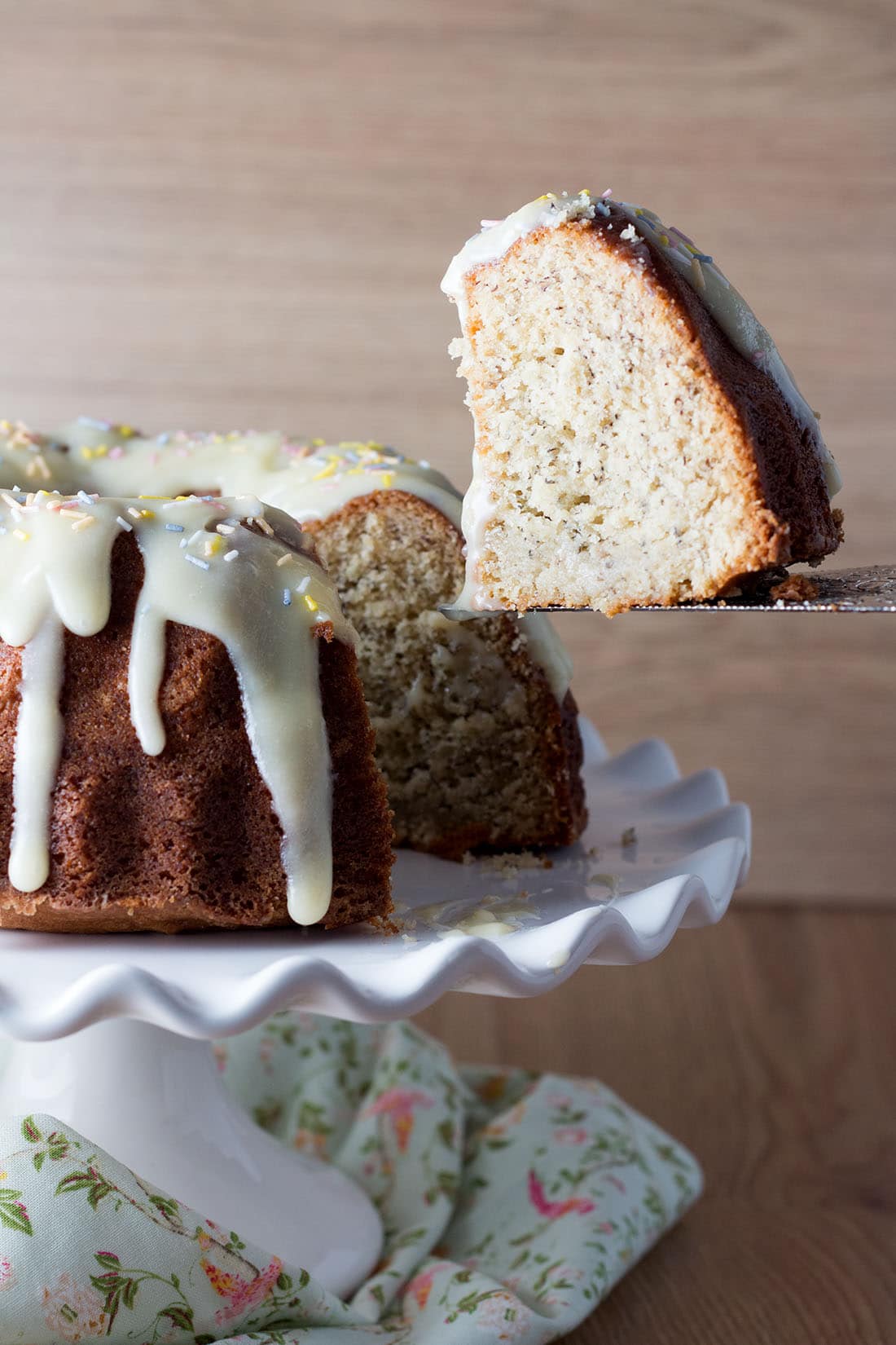 Vanilla Bean Banana Bundt Cake with Cream Cheese Icing with a slice being lifted from it