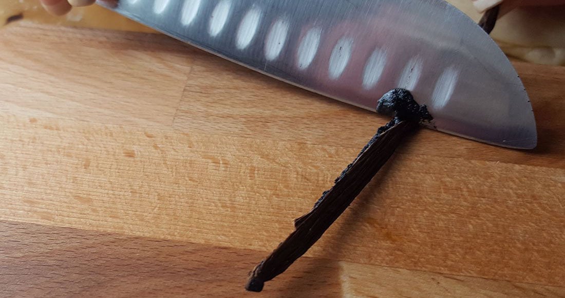 a knife scraping through a vanilla bean pod