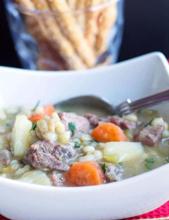 Classic Irish Stew in a bowl with a spoon and breadsticks