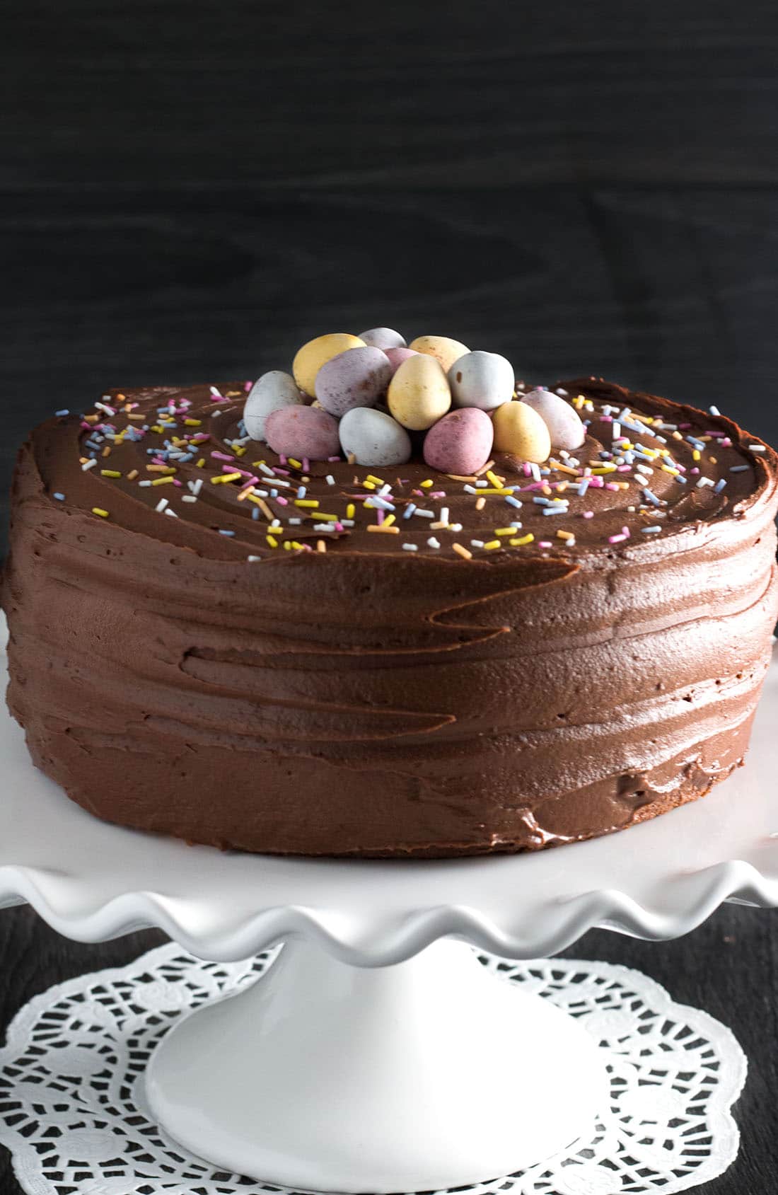 Yellow celebration cake with chocolate frosting on a serving dish topped with chocolate eggs