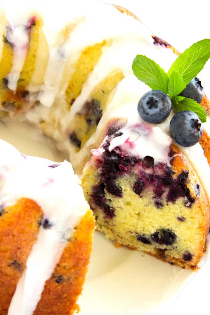 a Lemon Blueberry Bundt Cake with a slice cut out exposing the blueberry filled cake