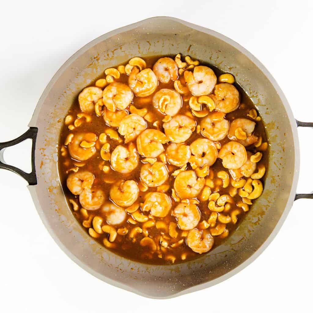 A skillet filled with 10 Minute Cashew Shrimp—shrimp and cashews cooked in a savory brown sauce, viewed from above on a white background.