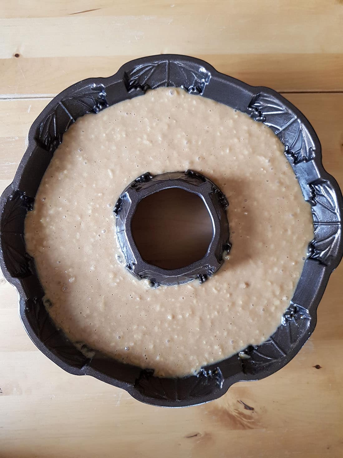 A close up of glazed apple bundt cake batter in a bundt pan