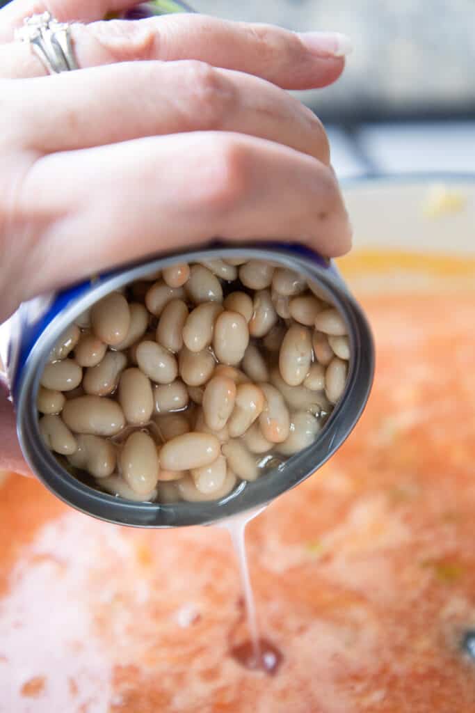 canellini beans being added to the soup