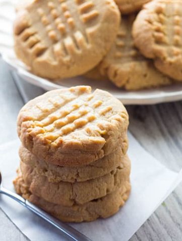 A stack of Classic Peanut Butter Cookies with a spoonful of peanut butter next to it