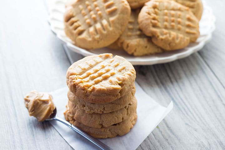 A stack of Classic Peanut Butter Cookies with a spoonful of peanut butter next to it