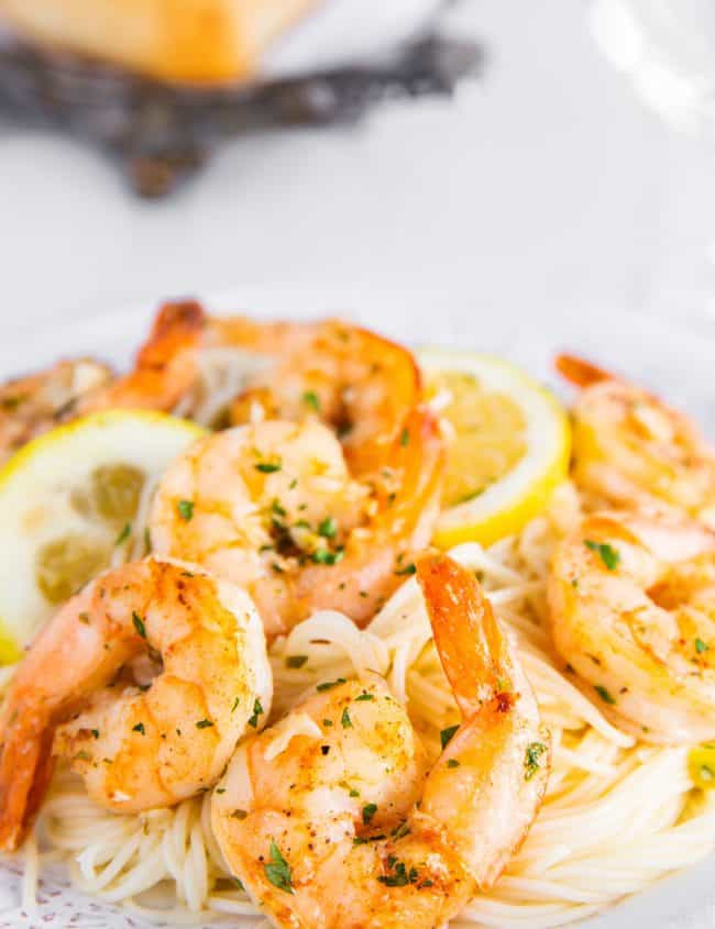 A plate full of shrimp scampi and spaghetti sprinkled with fresh chopped parsley