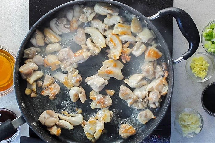 Chicken cut into bite sized pieces browning in a pan