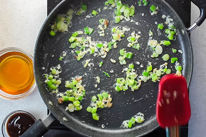 Onions, garlic and green onions in a wok stir frying in oil