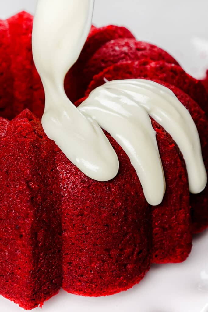 icing being spooned onto a  Red Velvet Bundt Cake